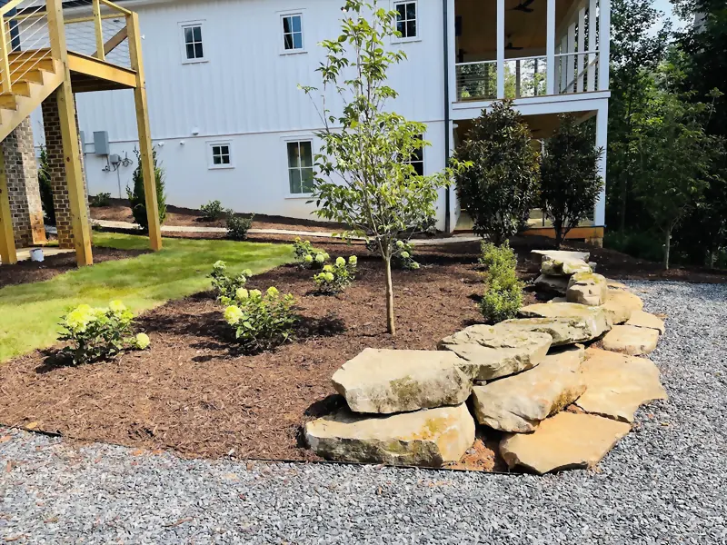 Flagstone boulder edging between a gravel drive and a newly planted bed