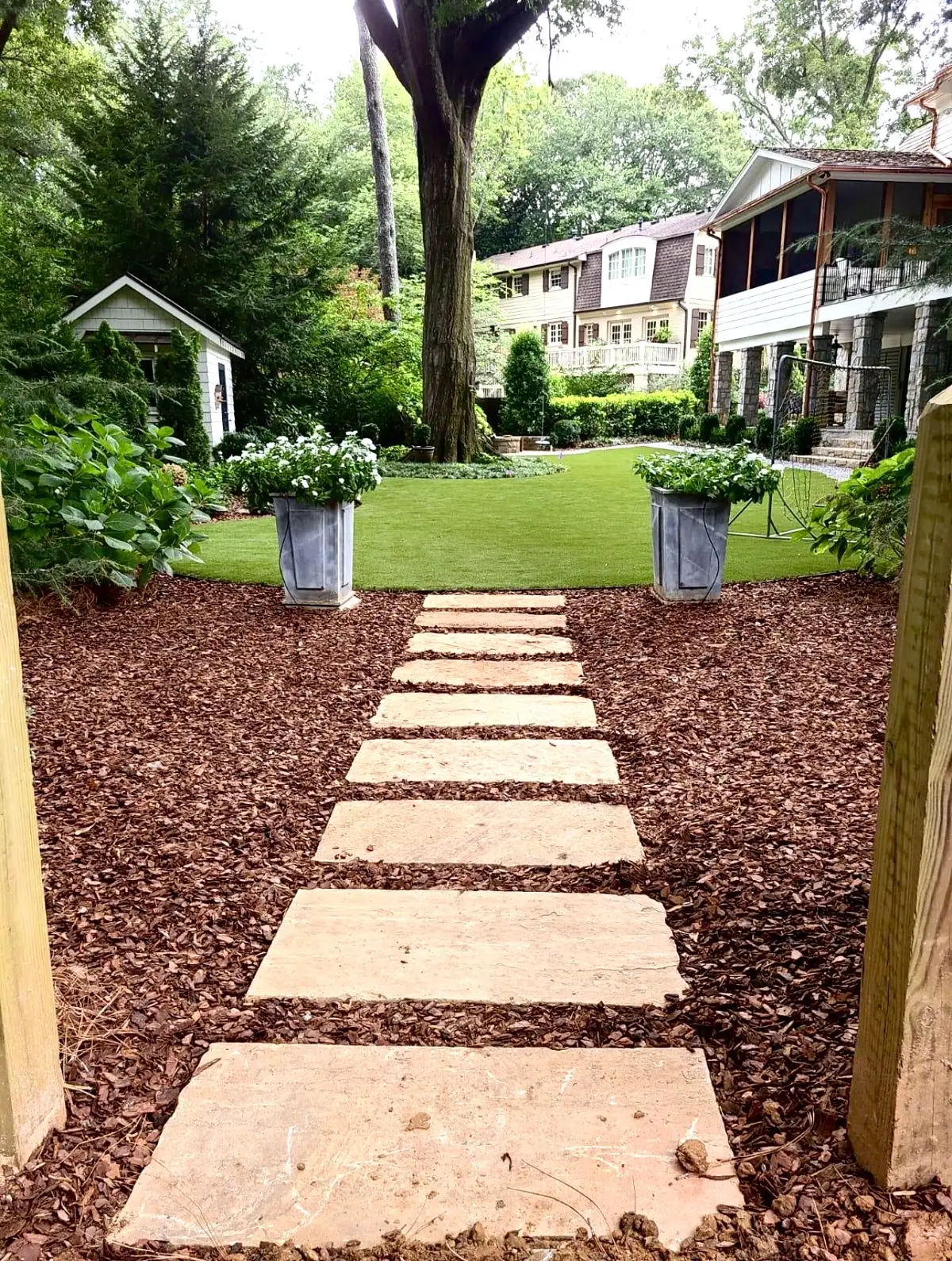 Sandstone stepping stones set through fresh mulch, leading past planters to a lawn
