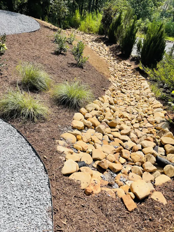 Stone-lined dry creek set over drainage pipe, carrying runoff away from the house