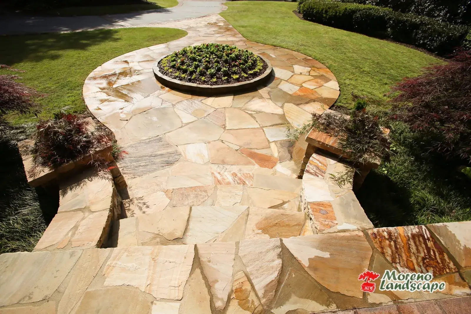 Flagstone patio built around a circular planted centerpiece with timber edging
