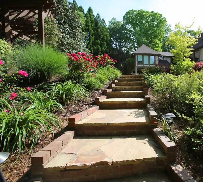 Flagstone and brick steps climbing a planted slope with azaleas, ornamental grasses and liriope