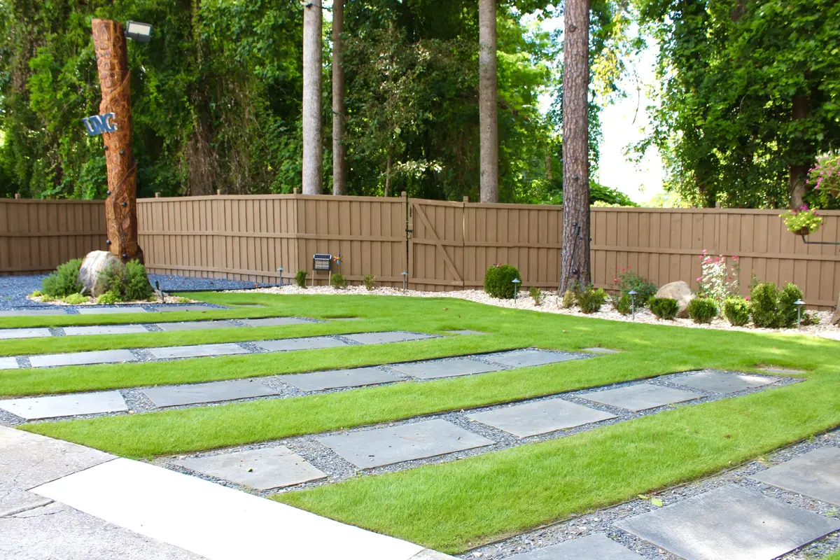 Large pavers set in ribbons of turf running the length of a fenced yard