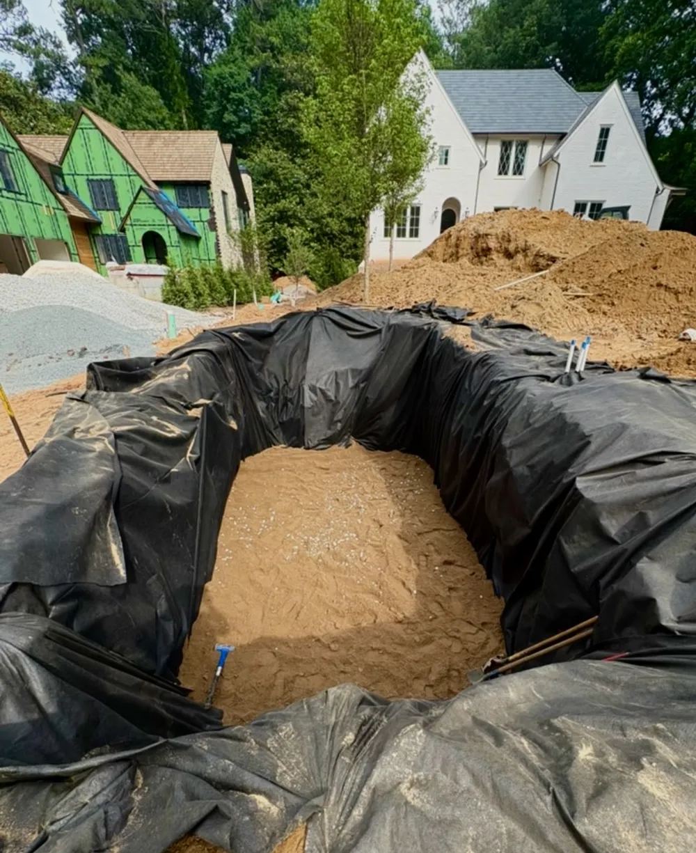 Infiltration trench lined with fabric and gravel during installation at a new build