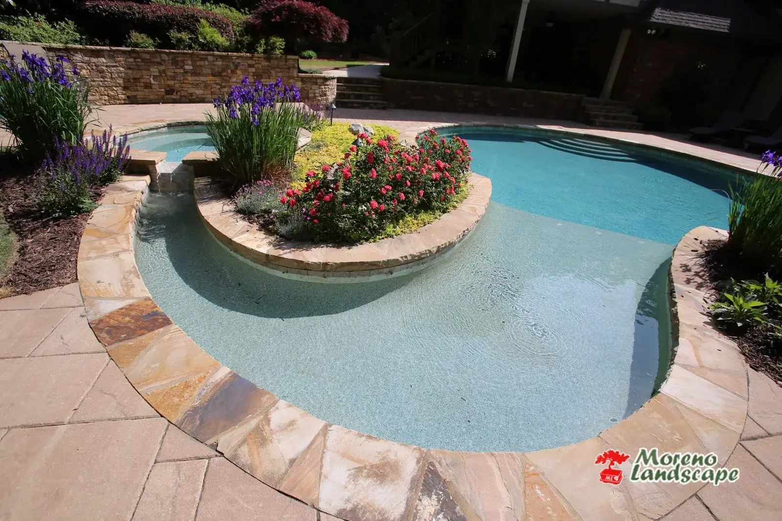 Free-form pool edged in flagstone with a raised planted island of lavender and annuals