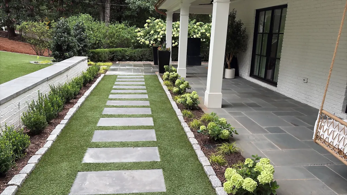 Bluestone stepping stones set into a turf strip running past hydrangeas to a covered porch