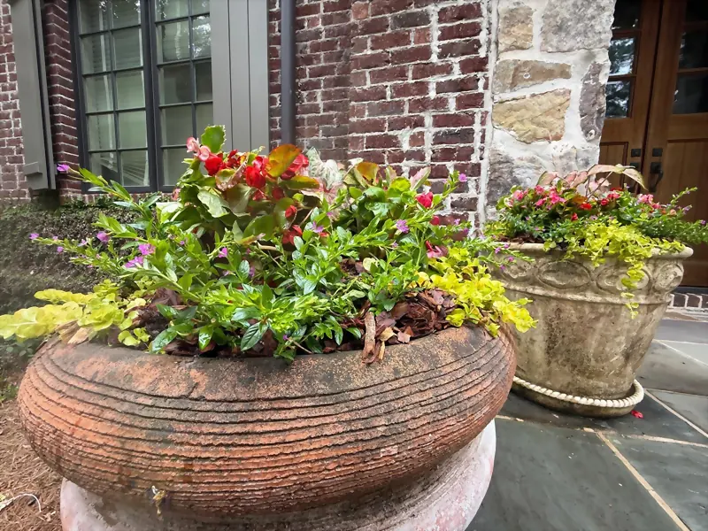 Stone urn planters of seasonal color flanking a front door